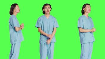 Male nurse nodding on camera and saying yes, showing approval and agreement gesture over greenscreen backdrop. Pleased medical assistant doing good symbol, agreeing with something. video