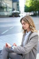 vertical Disparo de mujer de negocios mirando a hora en su mirar, esperando para compañero de trabajo, teniendo un negocio reunión al aire libre foto