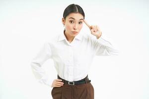 Corporate woman looks annoyed, points finger at head, mocks someone, scolding person, white background photo