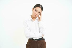 Portrait of confident businesswoman, korean woman with concerned face, looks serious at camera, white studio background photo