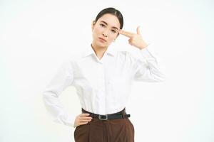 Portrait of annoyed business woman, holds fingers near head with bothered face expression, white background photo