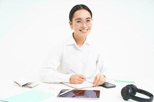 Office work and business. Young professional female employer, team leader sitting at workplace with digital tablet, smiling at camera, white background photo