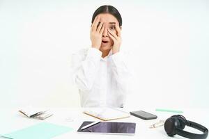 Image of asian office lady shuts her eyes embarrassed, sees something scary, sits at workplace, white background photo