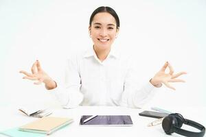 lugar de trabajo y trabajando ambiente. joven mujer se sienta en oficina con tableta y documentos, mantiene calma, medita y sonrisas, relaja, blanco antecedentes foto