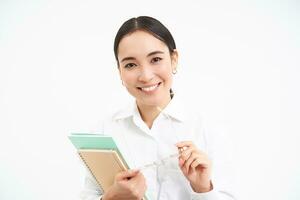 exitoso joven asiático mujer, profesor con cuadernos, mirando confidente y sonriente, blanco estudio antecedentes foto