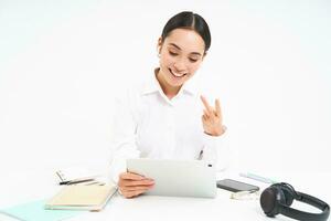 Image of saleswoman, asian businesswoman video chats, has online meeting on digital tablet, sits in her office, isolated on white background photo
