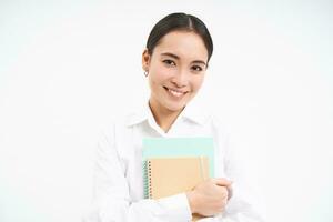 retrato de joven asiático mujer, Lanza libre tutor, sostiene cuadernos, trabajos y estudios, soportes terminado blanco antecedentes foto