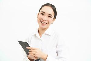 Corporate asian woman, manager using digital tablet, working on gadget, checking charts, company statistics, standing over white background photo