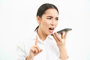 Angry korean saleswoman, shouting at smartphone speaker, screaming at mobile phone, scolding employee on cellphone, white background photo