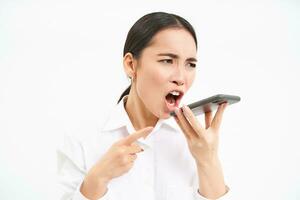 Angry korean saleswoman, shouting at smartphone speaker, screaming at mobile phone, scolding employee on cellphone, white background photo