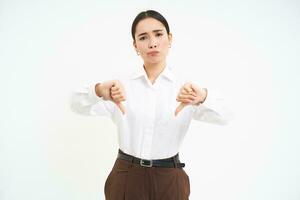 Image of disappointed woman, manager shows thumbs down and frowns with disapproval, white background photo