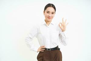 Business. Professional businesswoman, shows okay, approval gesture, recommends smth, white studio background photo