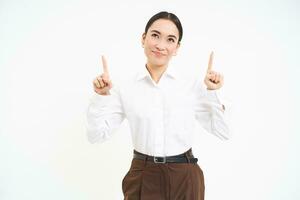 Image of female entrepreneur, points fingers up, shows advertisement on top, smiles with pleased face, white background photo