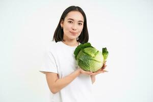 Lovely smiling woman, holding cabbage, posing with lettuce against white background photo