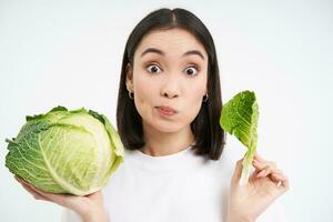 cerca arriba de linda coreano mujer, comiendo repollo, en dieta, participación lechuga, aislado en blanco antecedentes foto