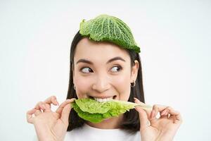 Portrait of asian girl with leaf on head, eats cabbage and smiles, isolated on white background photo