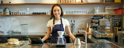 sonriente niña barista fabricación de cerveza filtrar café preparando orden en cafetería, en pie a mostrador foto