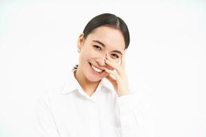 Beautiful young korean woman, laughing and smiling, showing sincere happiness and joy, standing over white background photo