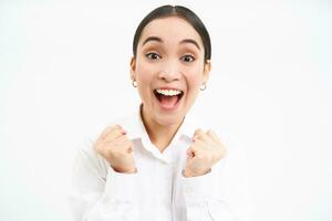 Enthusiastic asian businesswoman, office manager jumps from success, celebrates and rejoices, stands over white background photo