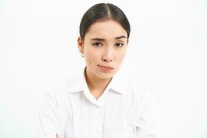 Asian woman professional, looks with skeptical, disbelief face, unsure of smth, stands isolated on white background photo