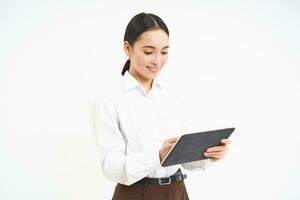 Corporate and young entrepreneurs concept. Successful businesswoman using digital tablet, prepares for meeting, looks at business concept on her gadget photo