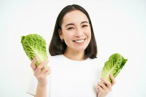 contento coreano mujer vegetariano, sonriente y demostración repollo, comiendo lechuga en dieta, Guías activo estilo de vida, blanco antecedentes foto