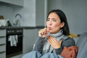 enfermo coreano mujer tos y sensación indispuesto, haciendo muecas, tiene influenza, tosió frío o gripe, quedarse a hogar foto