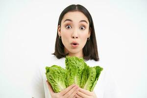 Happy woman vegetarian looks at delicious lettuce, likes eating fresh cabage, vegan food, white background photo