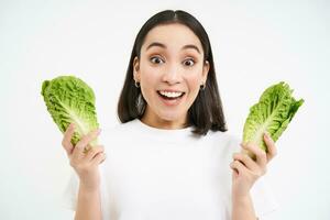 Healthy diet and organic food. Smiling asian woman showing cabbage, eating lettuce, cleansing her body, on detox, white background photo