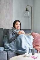 Korean woman feels unwell, sneezing and coughing, catching cold, staying at home with fever and temperature, taking medication photo