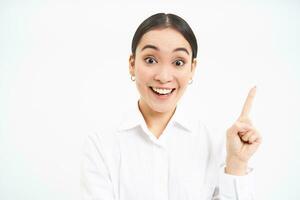 Smiling businesswoman, asian office manager pointing right, showing advertisement aside on empty copy space banner, standing over white background photo