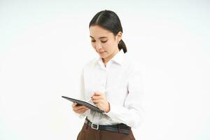 Corporate and young entrepreneurs concept. Successful businesswoman using digital tablet, prepares for meeting, looks at business concept on her gadget photo