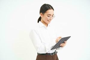 Beautiful asian woman, entrepreneur with digital tablet, working on business project, leading meeting and looking at notes on device, white background photo