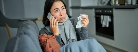 Portrait of sick woman calling her medical clinic, phone call appointment with GP, caught cold and stays at home photo