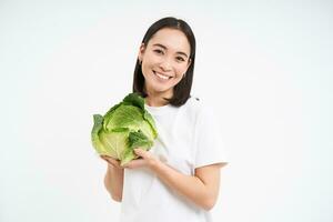 hermosa coreano mujer, participación repollo y sonriente, aislado en blanco estudio antecedentes foto