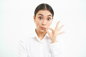 Young asian office lady, manager zips her lips, shows mouth seal gesture, keeps secret, stays quiet, stands over white background photo