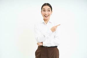 Image of asian businesswoman points finger to the right, shows advertisement, demonstrates banner, white background photo