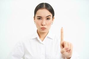 Rule number one. Serious and confident office manager, businesswoman shows finger with disapproval, dislike smth, white background photo