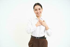 sonriente coreano mujer, sostiene manos en corazón, mirando con cuidado y amar, aislado terminado blanco antecedentes foto