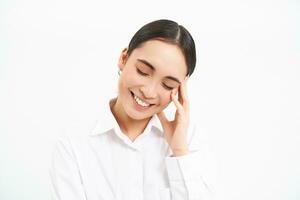 cerca arriba retrato de contento mujer de negocios, asiático oficina dama reír, sonriente y mirando despreocupado, en pie terminado blanco antecedentes foto