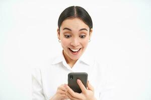 Business and corporate people. Young asian female entrepreneur, looking at smartphone, working on mobile phone, standing over white background photo