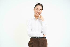 Thoughtful businesswoman, looks aside and thinks, plans smth, stands over white background photo