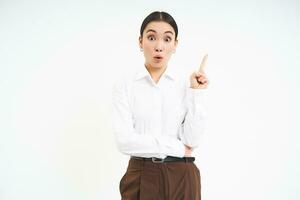 Enthusiastic asian woman, entrepreneur points up, eureka gesture, has an idea, came up with solution, white background photo