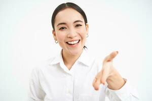 Asian businesswoman extends hand for handshake, team leader introduces herself and smiles friendly, stands confident on white isolated background photo