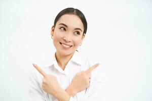 Smiling korean woman points sideways, showing left and right, businesswoman making choice, demonstrates two banners, white background photo