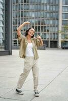 Girl dances on street with headphones on, listens to music and feels happy walking in city photo