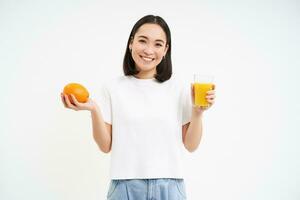 hermosa y sano joven mujer, empieza su día con Fresco jugo, participación naranja Fruta y sonriente, blanco antecedentes foto