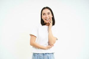 retrato de sincero, sonriente asiático mujer, riendo y sonriente, posando en camiseta y pantalones terminado blanco antecedentes foto