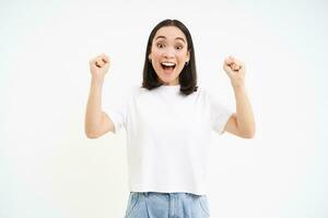 entusiasta asiático mujer, cantando, celebrando victoria, enraizamiento para equipo, en pie emocionado terminado blanco antecedentes foto