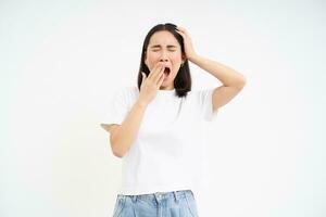 Exhausted female student, girl yawns and looks sleepy, standing tired, white studio background photo